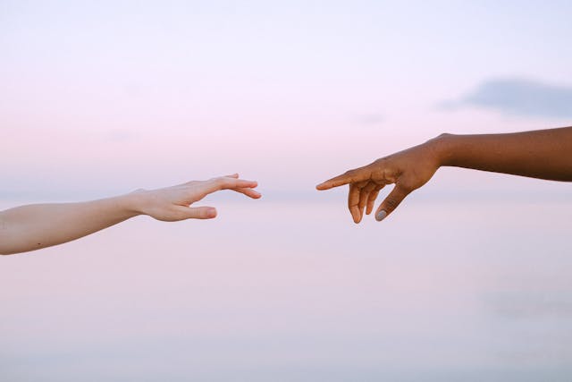 兩隻手指在夕陽下彼此靠近卻未接觸，象徵親密關係中的心理界線與適度距離