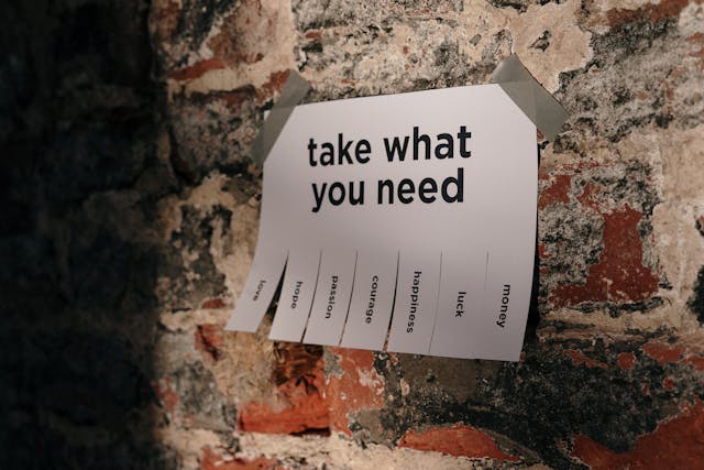 一張貼在牆上的紙條寫著『take what you need』，下方列出愛、希望、熱情、勇氣、快樂、幸運、金錢等選項，象徵人生有限但選擇繁多，引發FOMO焦慮。