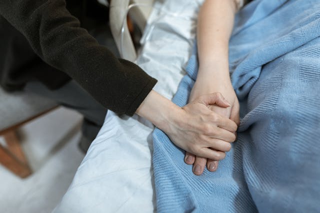 病床上的患者與親人緊緊握住彼此的手，象徵臨終關懷、陪伴與愛的連結