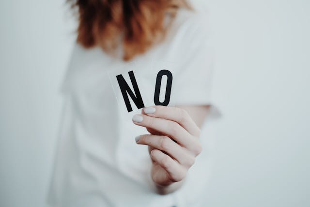 一位女孩身穿白色衣服拿著NO的字母標誌。
