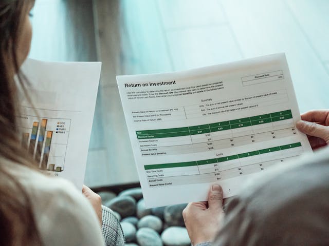兩位專業人士正在檢視 ROI 報表與圖表，用於財務分析與投資決策