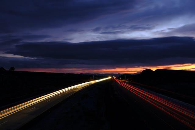 夕陽下的高速公路車軌延伸至遠方盡頭，象徵追尋人生意義的漫長旅程。