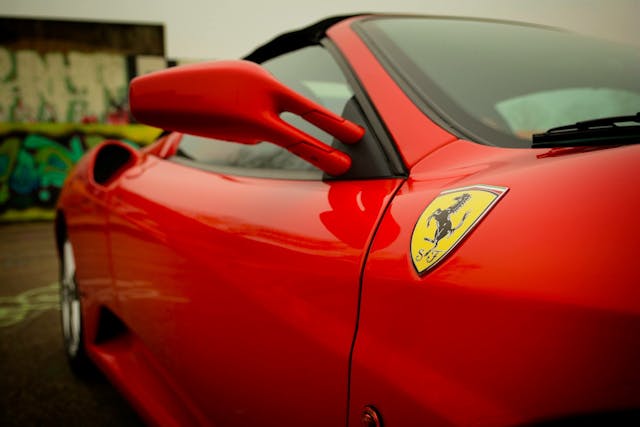 紅色 Ferrari 法拉利跑車特寫，顯示經典躍馬標誌，象徵豪華車市場的品牌定位