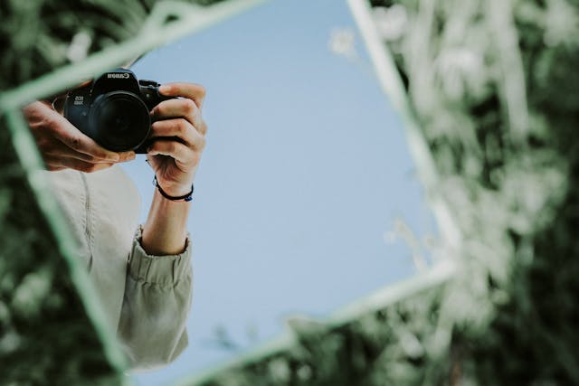 相機透過鏡子反射被拍攝的瞬間，呈現拍攝者手持相機的特寫畫面。